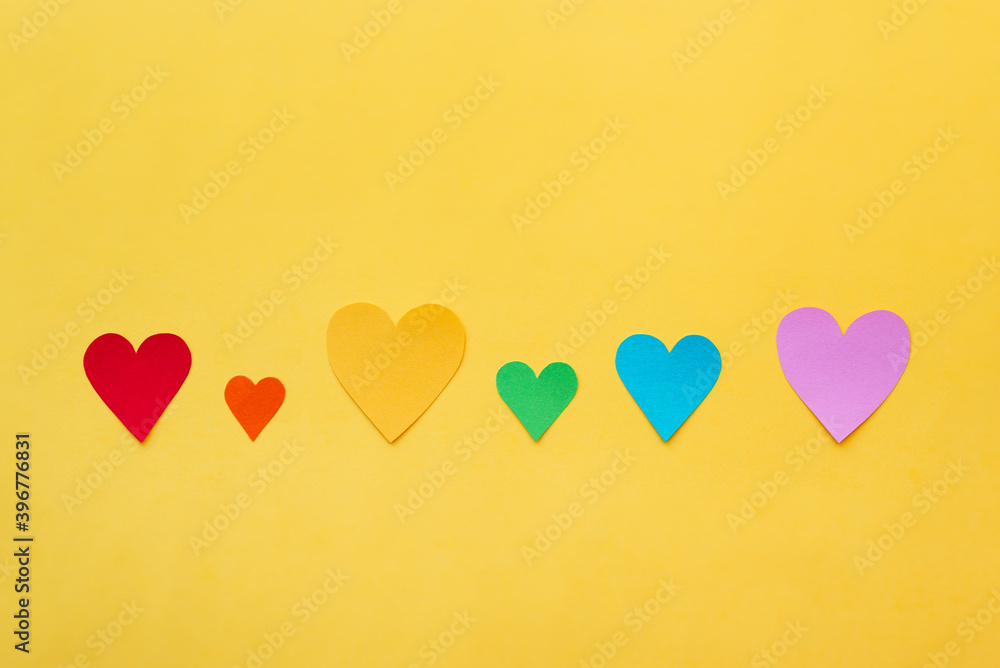 Colorful paper hearts on yellow background. Concept of love.