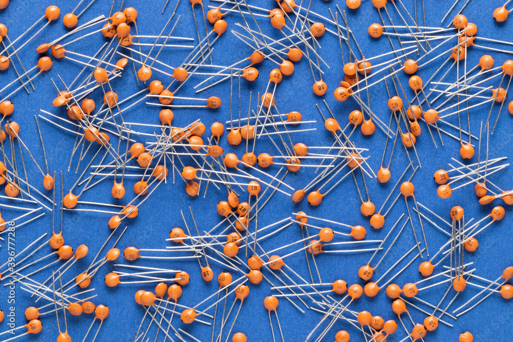 Radio components. Disc ceramic capacitor of orange color on a blue background close-up. Capacitor specifications: 18pF 50v.