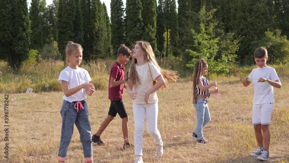 Group of happy kids blow soap bubbles in summer park Group of happy kids blow soap bubbles in summer park