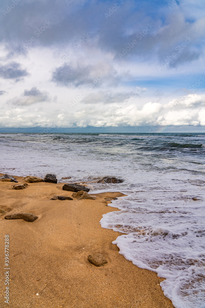 Empty beach and stormy sea in cloudy weather