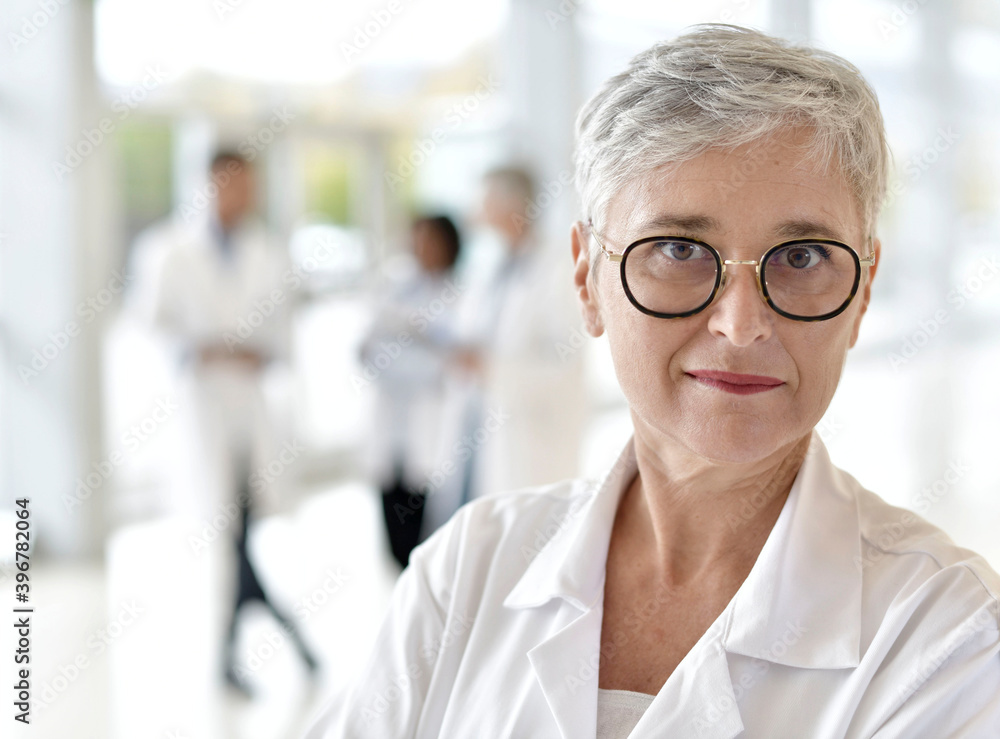 Portrait of smiling mature woman doctor standing in hospital hallway Portrait of smiling mature woman doctor standing in hospital hallway