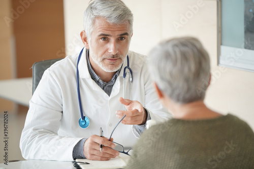 Mature doctor with patient in office
