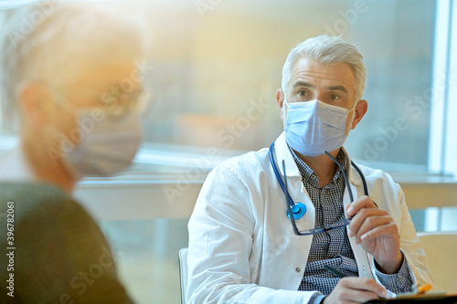 Doctor with face mask listening to patient in office, 19-ncov pandemic