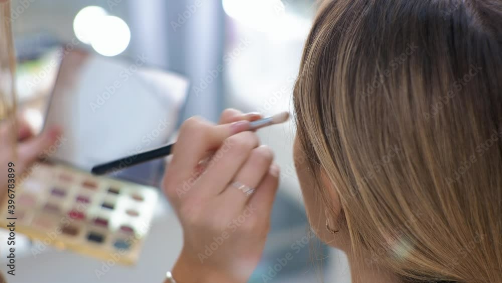Young brunette woman make-up artist paints a blonde girl in a beauty salon. Eyeshadows. Young brunette woman make-up artist paints a blonde girl in a beauty salon. Eyeshadows.
