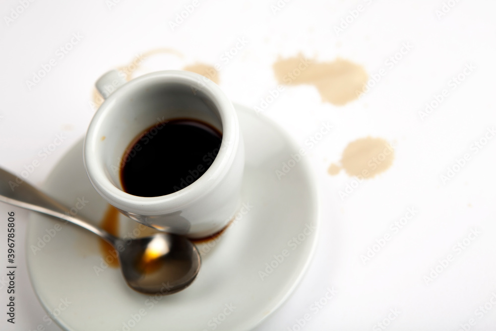 Espresso cup with silver spoon. Coffee stains on the side. Selective focus on object. Espresso cup with silver spoon. Coffee stains on the side. Selective focus on object.