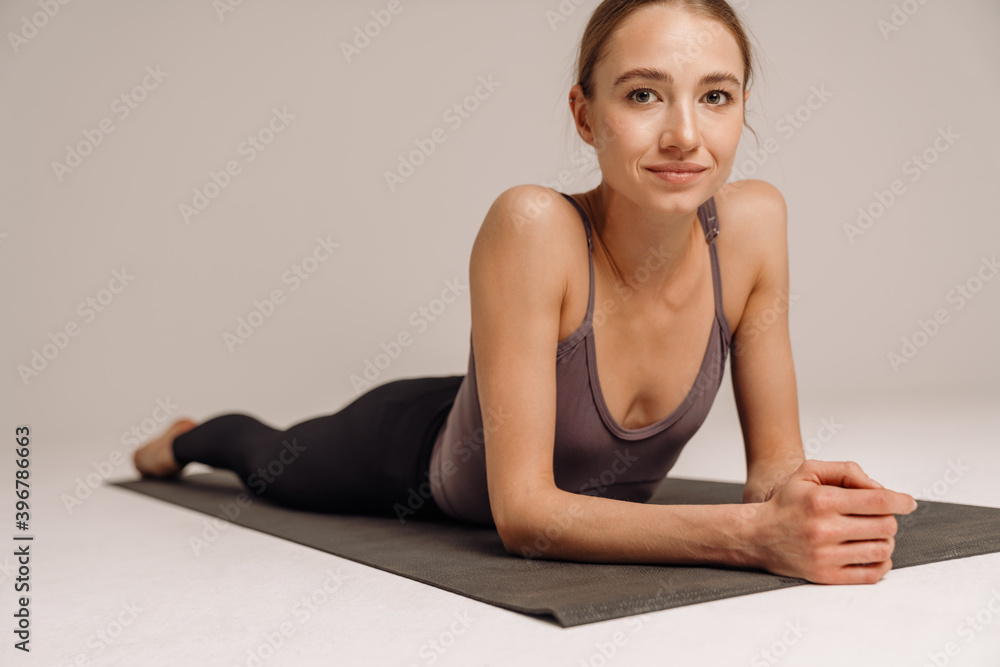 Fototapeta premium Beautiful pleased sportswoman resting while working out on mat