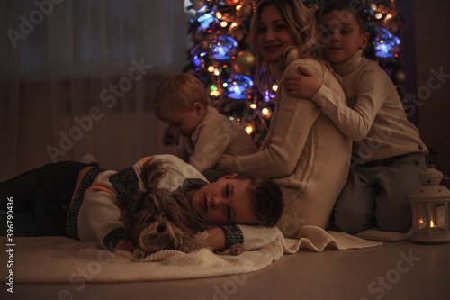 Happy family, single mother and sons celebrate the xmas in the evening near christmas tree
