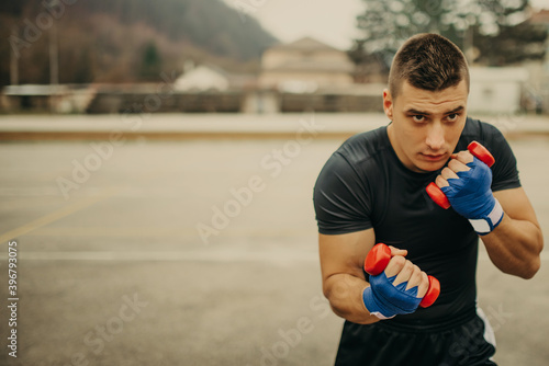 Handsome young man boxer practicing shadow boxing with dumbbells © Minet