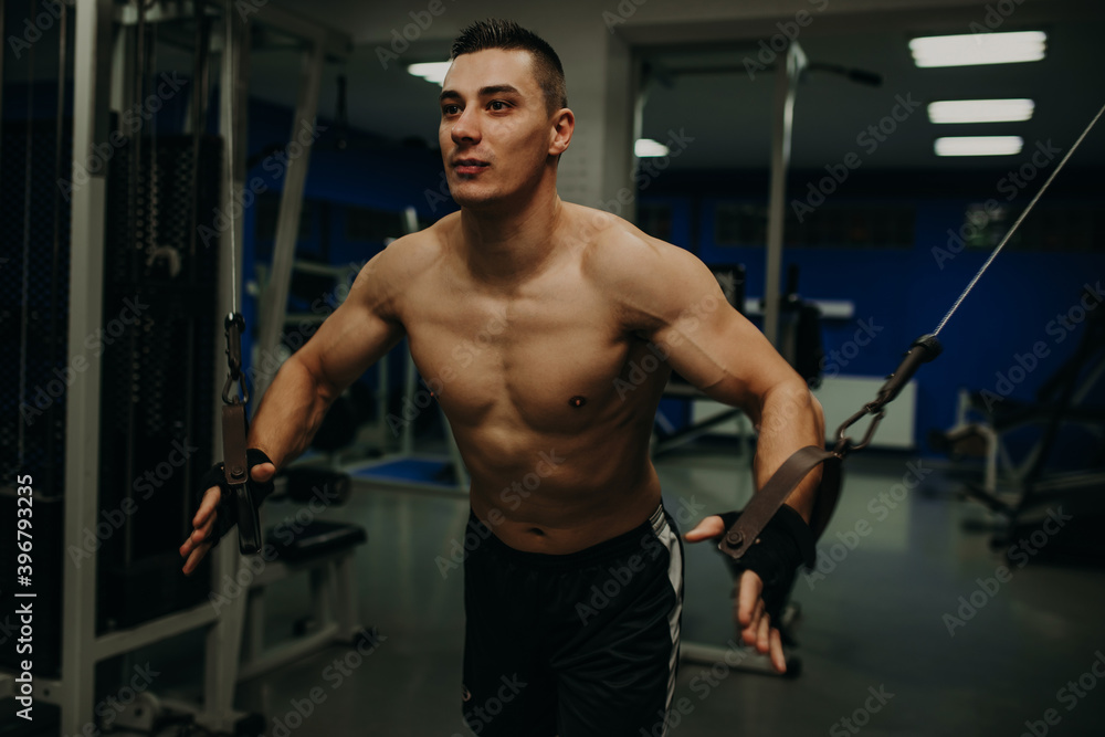 One man exercising suspension training trx in dark gym One man exercising suspension training trx in dark gym