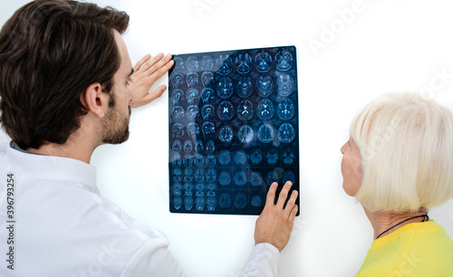 Doctor shows to an elderly woman the results of MRI scan of her brain. Diagnostics and treatment of brain diseases, headaches, tumors, and brain cancer photo