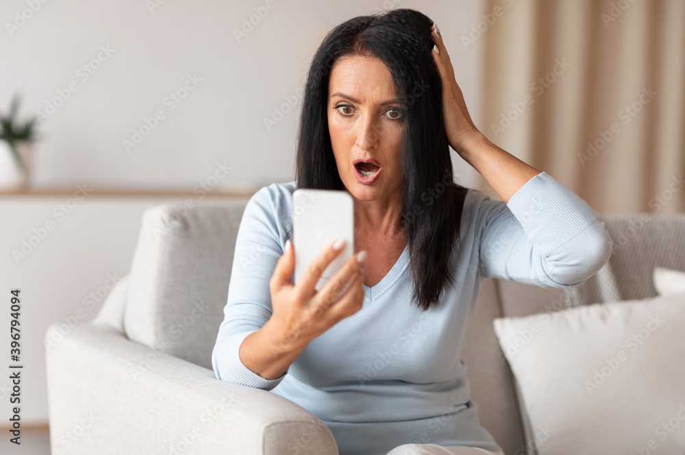 Surprised shocked mature woman using mobile phone Surprised shocked mature woman using mobile phone