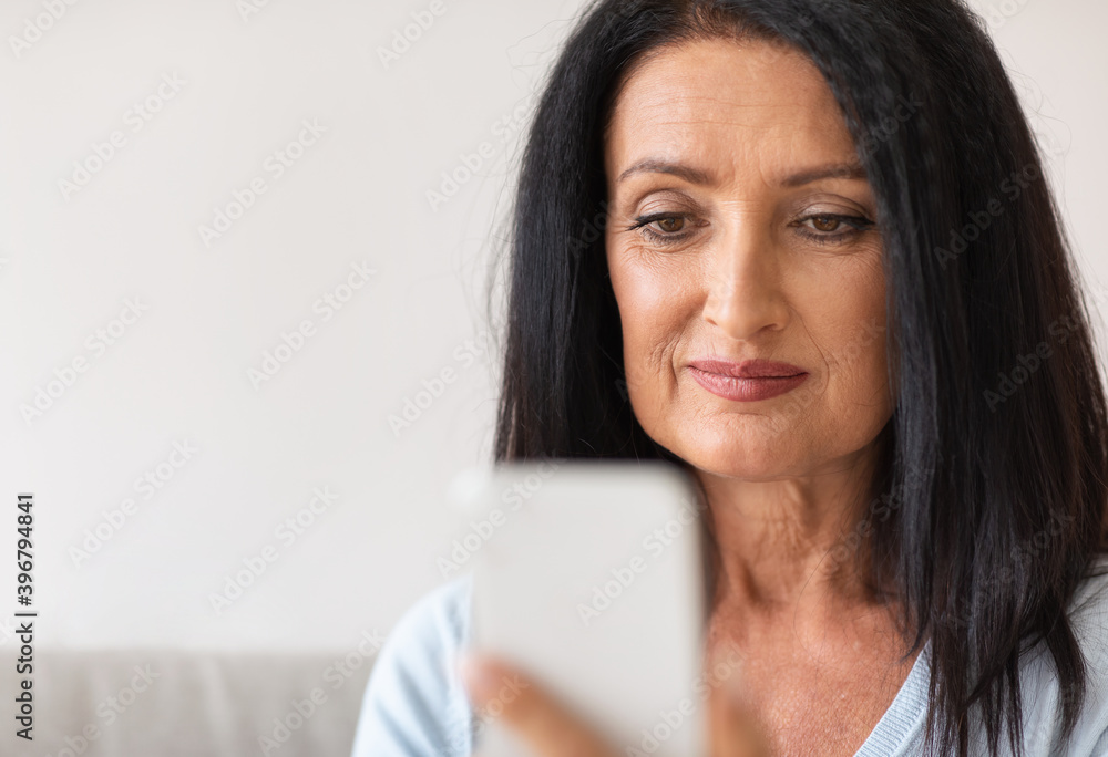 Smiling mature woman using mobile phone at her home Smiling mature woman using mobile phone at her home