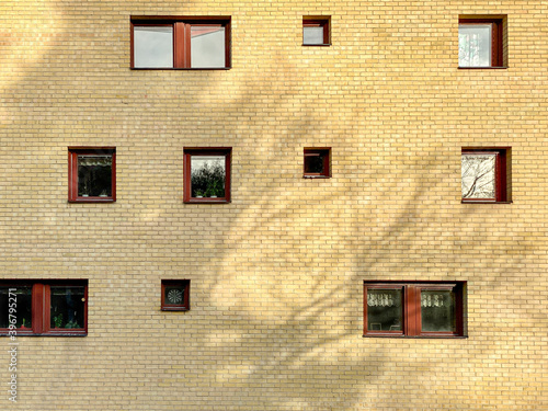 Many random placed windows on a yellow brick residential building outdoors.
