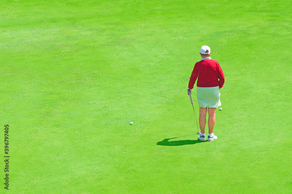 Woman golfer on golf course. Elderly golf player with golf stick on field