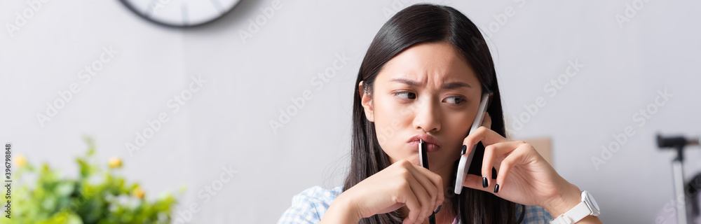 Portrait of thoughtful asian volunteer talking on smartphone on blurred background, banner