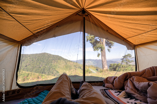 Man relaxing in a tent on hill with blue sky