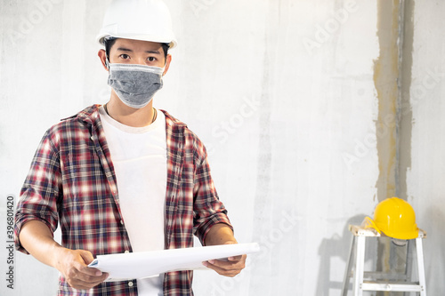 Portrait young asian foreman engineering home inspection building house wearing surgical mask with looking construction for check building home on job site to customers with new normol