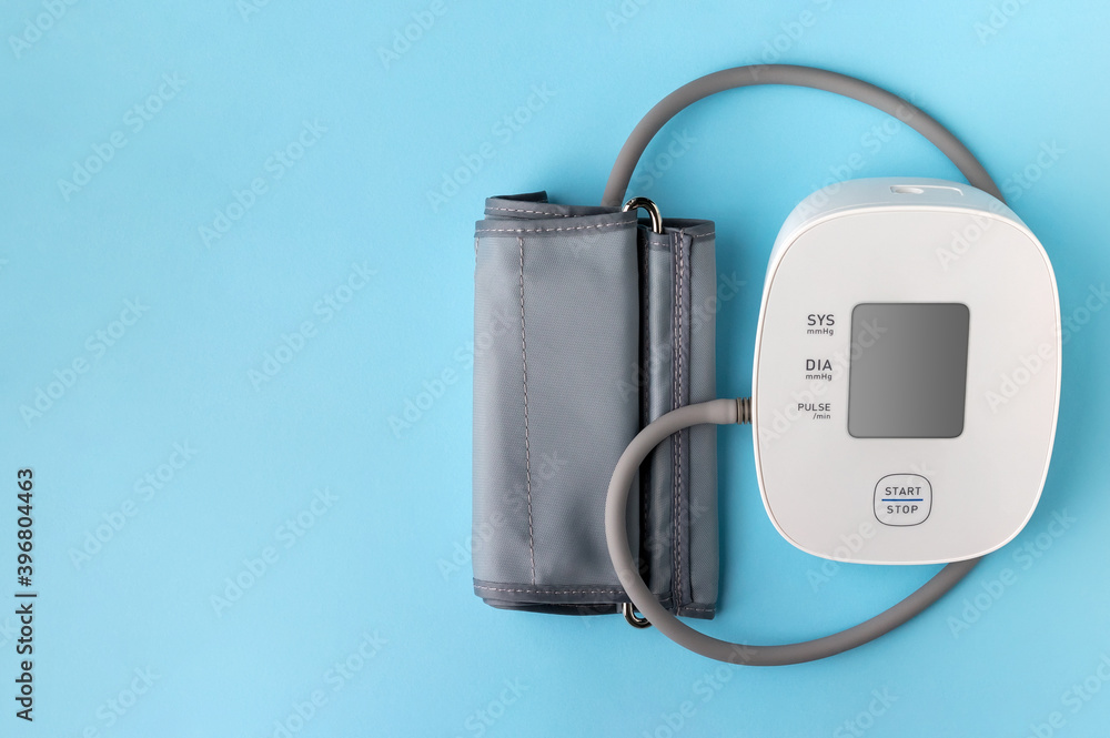 Automatic blood pressure monitor on blue background. Medical electronic tonometer with copy space Automatic blood pressure monitor on blue background. Medical electronic tonometer with copy space