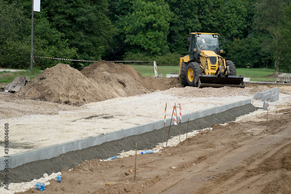 Construction site of new road in city. Yellow tractor. Piles of excavated ground. Construction site of new road in city. Yellow tractor. Piles of excavated ground.