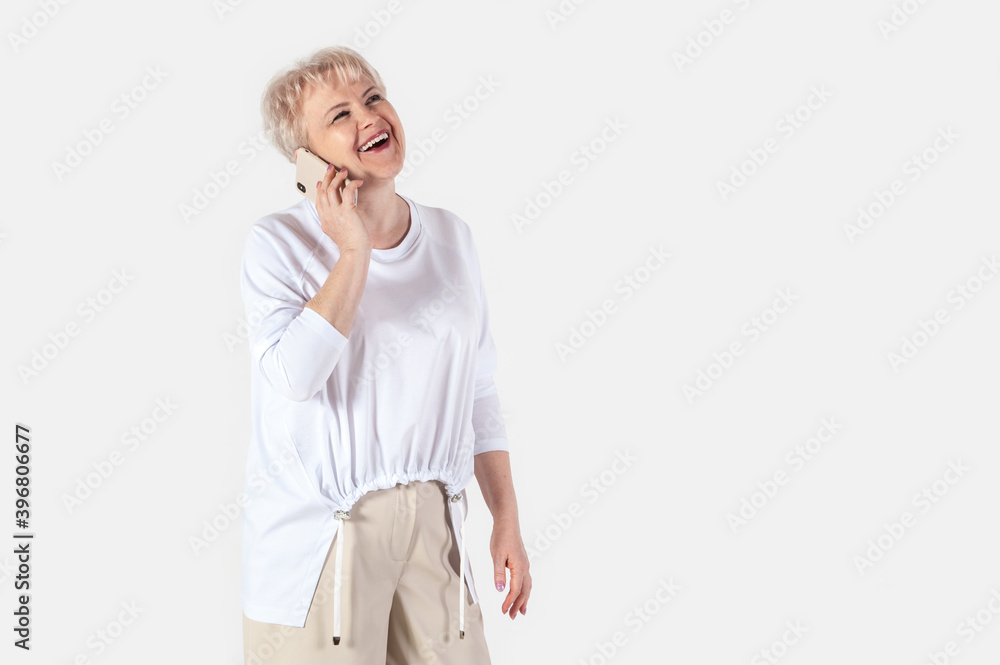 Portrait of a beautiful elderly woman, isolated on white background. Senior female talking by phone and laughing Portrait of a beautiful elderly woman, isolated on white background. Senior female talking by phone and laughing