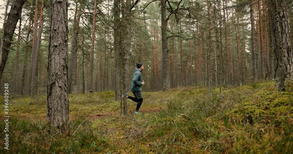 man in sportswear running through the forest on autumn day. outdoor training. slow motion slider shot man in sportswear running through the forest on autumn day. outdoor training. slow motion slider shot