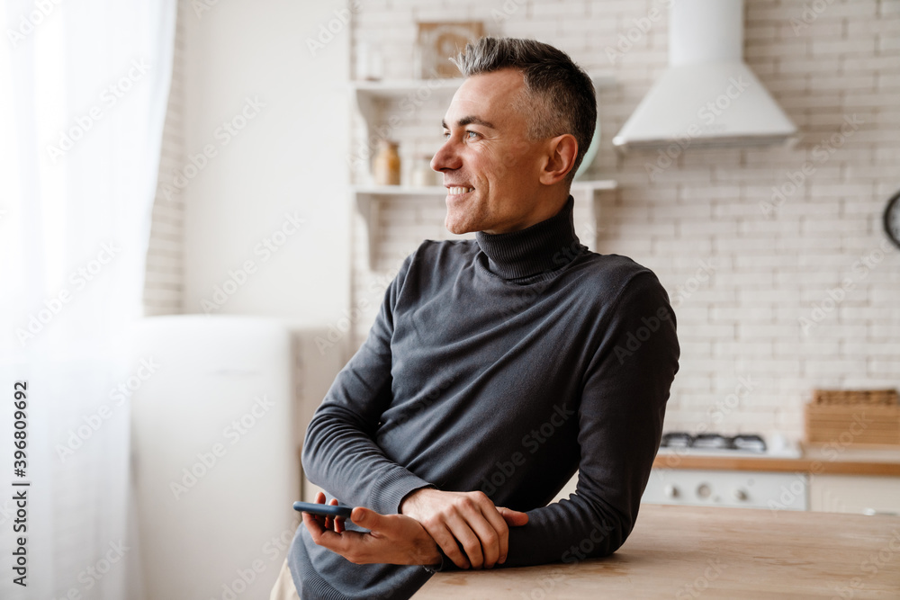 Handsome smiling man using mobile phone while leaning on table