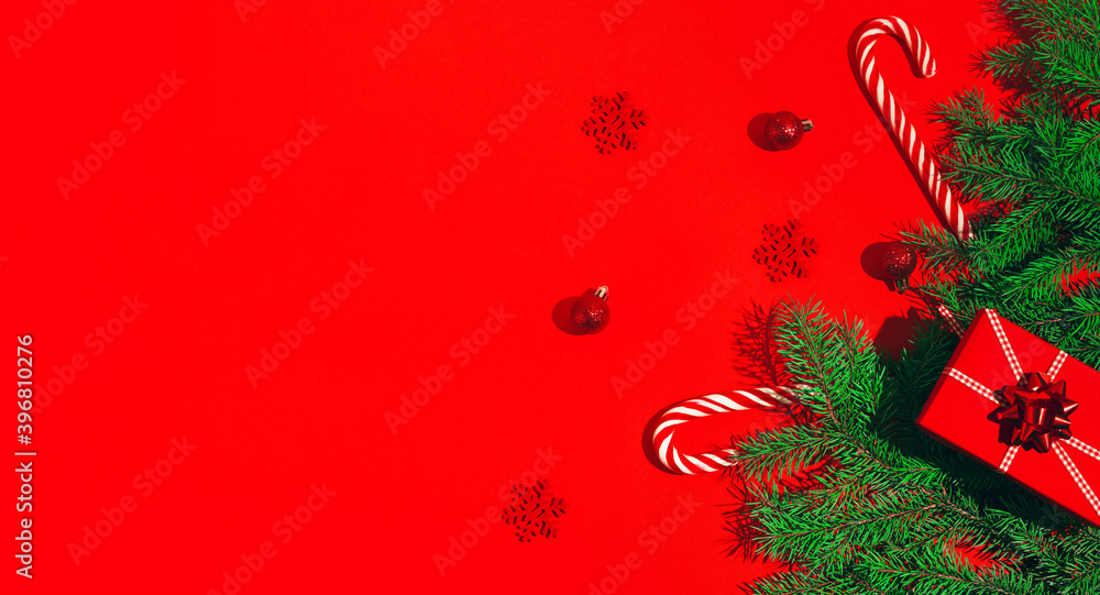 Winter composition with red present box, lollipos, decorative snowflakes and green fir tree branch.