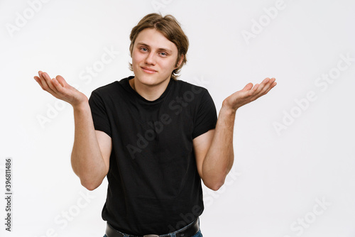 Confused young man doubting shrugging shoulders photo