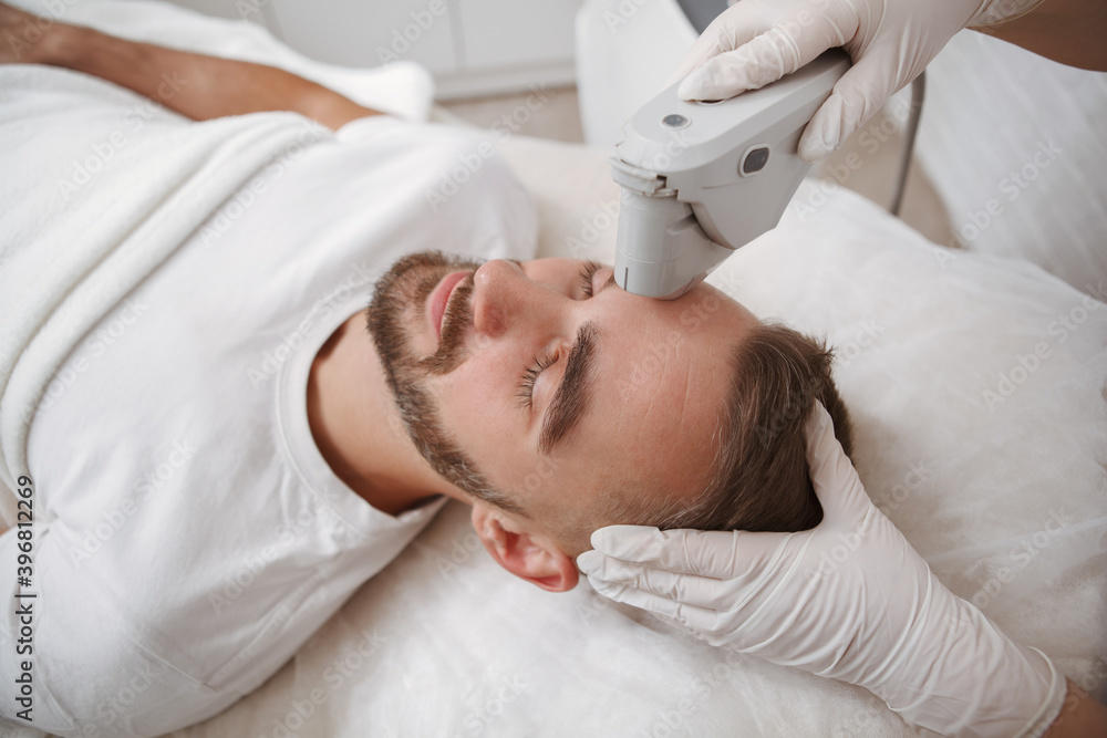 Top view shot of a man getting facial treatment by cosmetologist