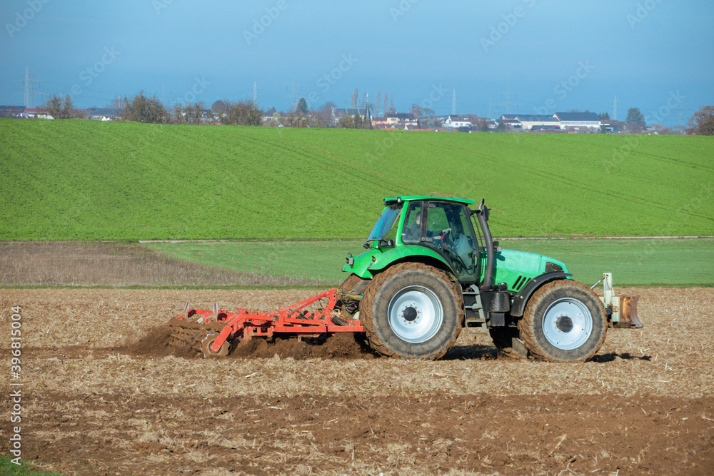 Fototapeta premium Traktor mit Egge auf einem Acker
