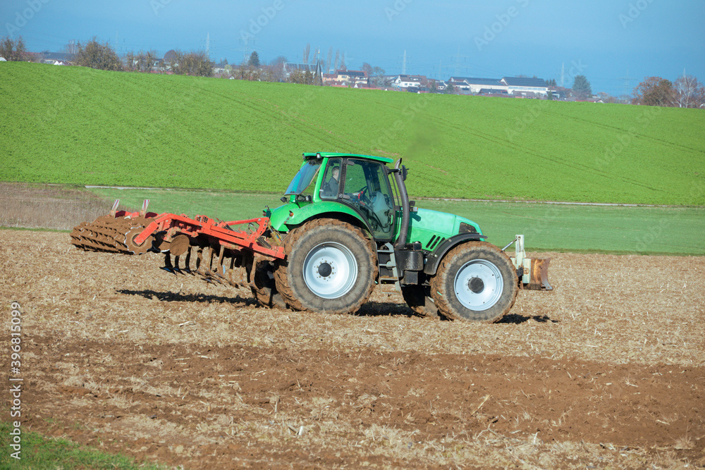 Fototapeta premium Traktor mit Egge auf einem Acker