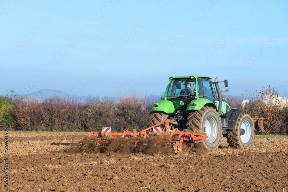 Fototapeta premium Traktor mit Egge auf einem Acker