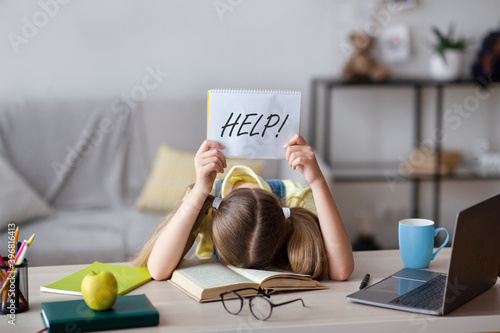 Sad school girl sleeping and holding paper asking for help photo