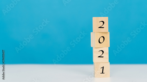 Wooden cube 2021 word on blue background.goal, business and New Year holiday concepts