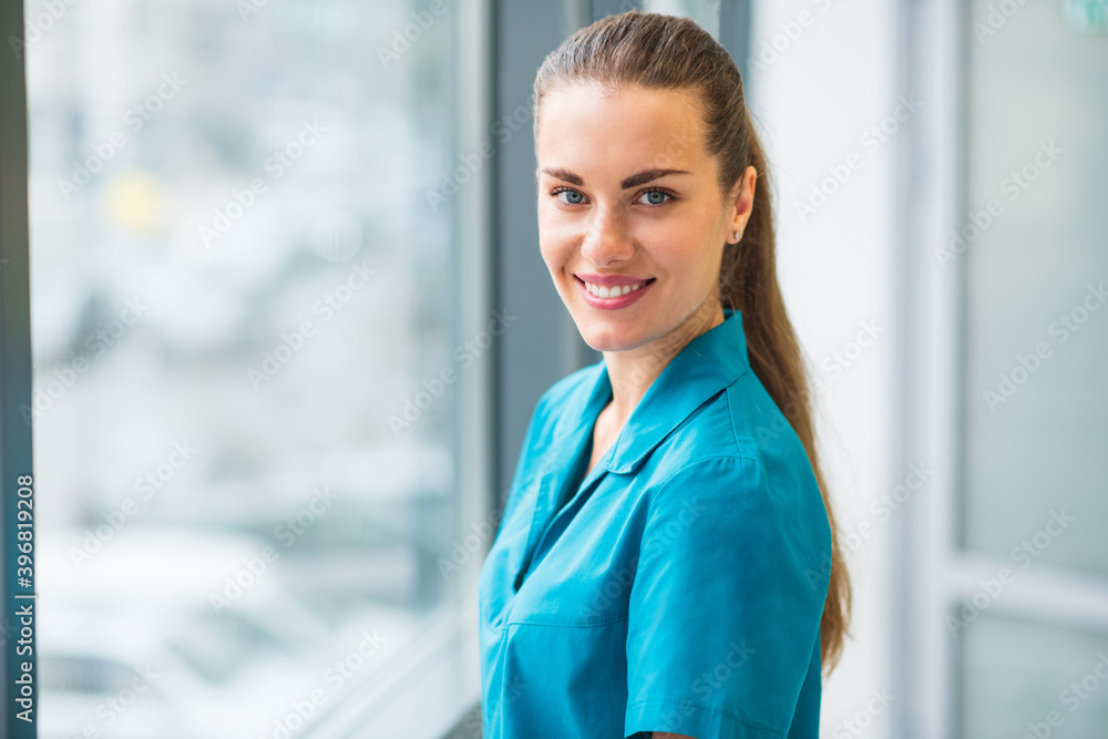 Pretty young female doctor in blue uniform smiling nicely Pretty young female doctor in blue uniform smiling nicely