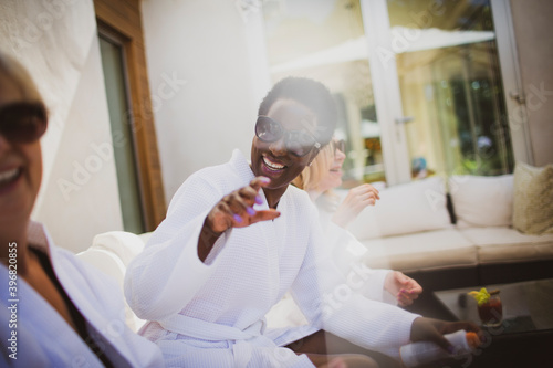 Happy senior women friends in spa robes and sunglasses on hotel patio