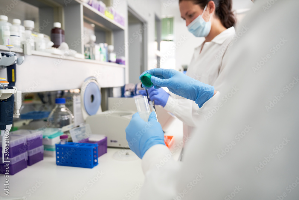 Female scientists in gloves and face mask working in laboratory Female scientists in gloves and face mask working in laboratory