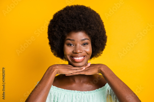 Photo portrait of cute girl with hands under chin isolated on vivid yellow colored background