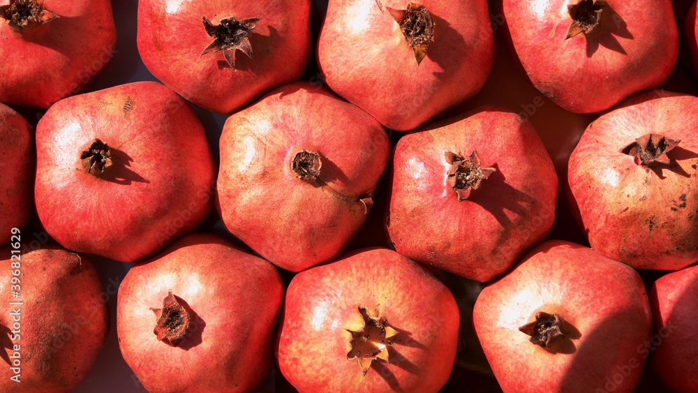 Pile of red ripe pomegranate fruits at market stall. Heap of fresh fruits at street market on a sunny day. Exotic fruits background. Pile of red ripe pomegranate fruits at market stall. Heap of fresh fruits at street market on a sunny day. Exotic fruits background.