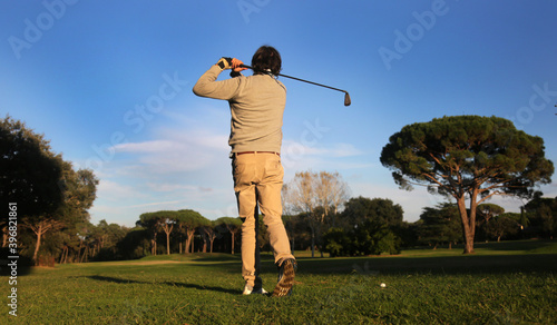 man playing golf in the course hitting the ball with swing