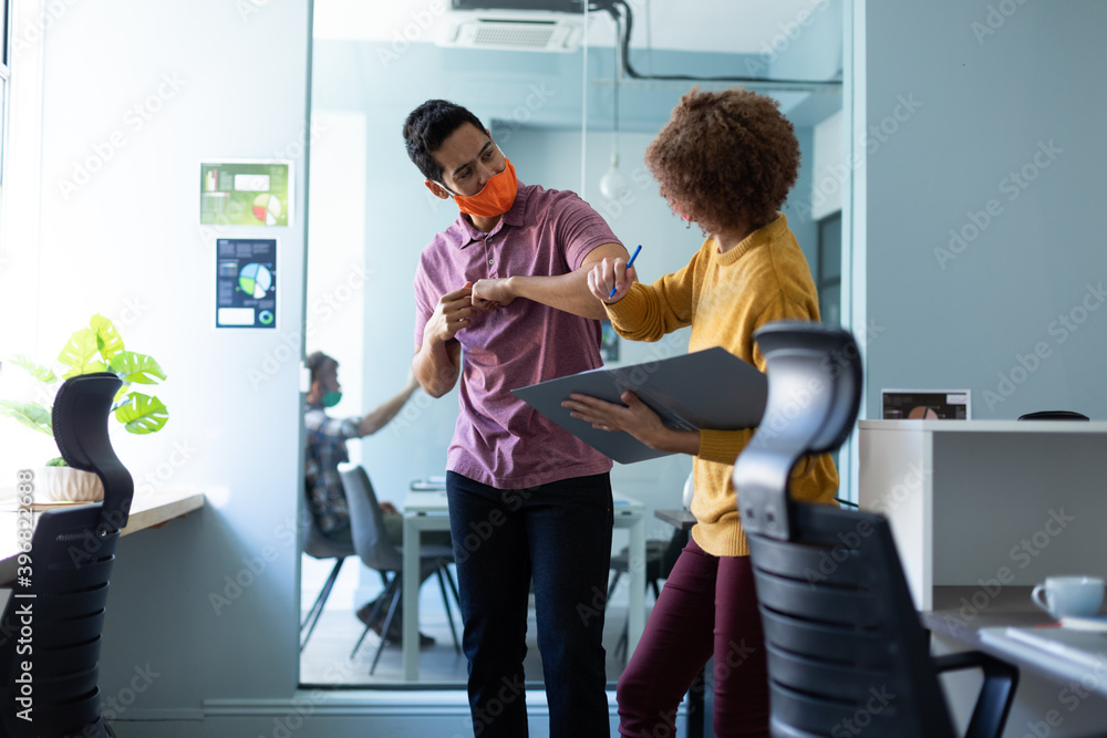 Mixed race man and woman wearing masks in an office Mixed race man and woman wearing masks in an office