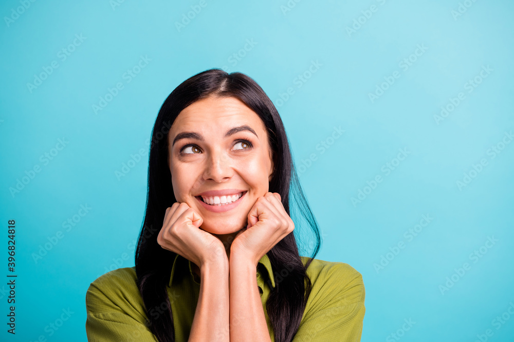 Photo of inspired young lady look up empty space hands chin beaming smile wear green shirt isolated blue color background Photo of inspired young lady look up empty space hands chin beaming smile wear green shirt isolated blue color background
