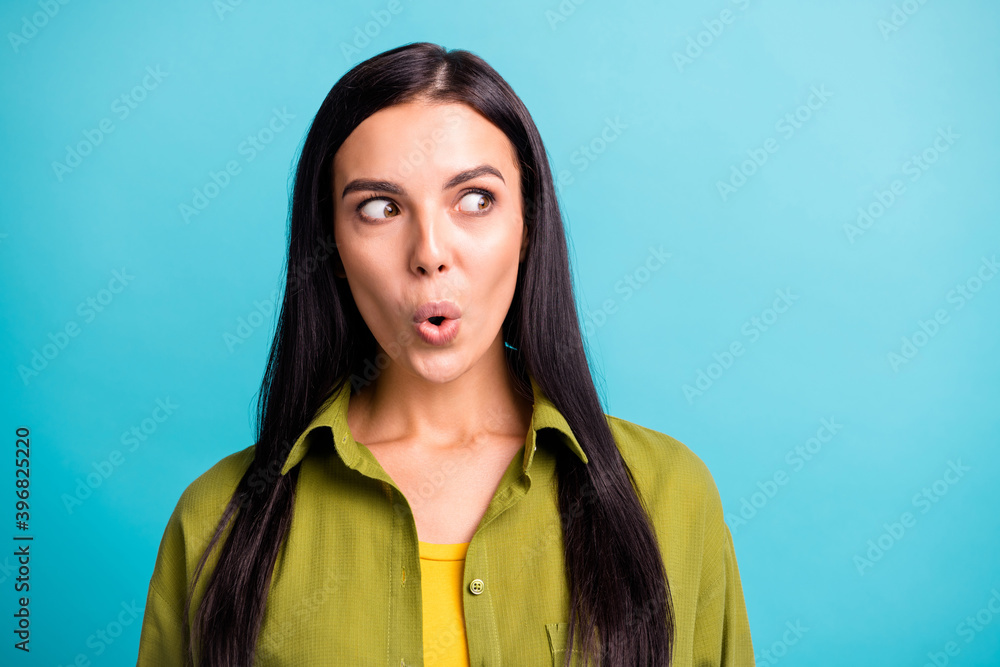 Photo of surprised young girl funny look side empty space wear green shirt isolated blue color background Photo of surprised young girl funny look side empty space wear green shirt isolated blue color background