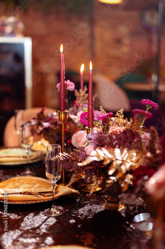 Flower arrangement on the table with pink gerbera and painted leaves gold color. Selected focus and blurred background