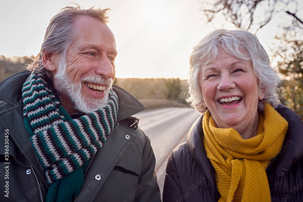 Portrait Of Loving Senior Couple Enjoying Autumn Or Winter Walk Along Country Road Together Portrait Of Loving Senior Couple Enjoying Autumn Or Winter Walk Along Country Road Together