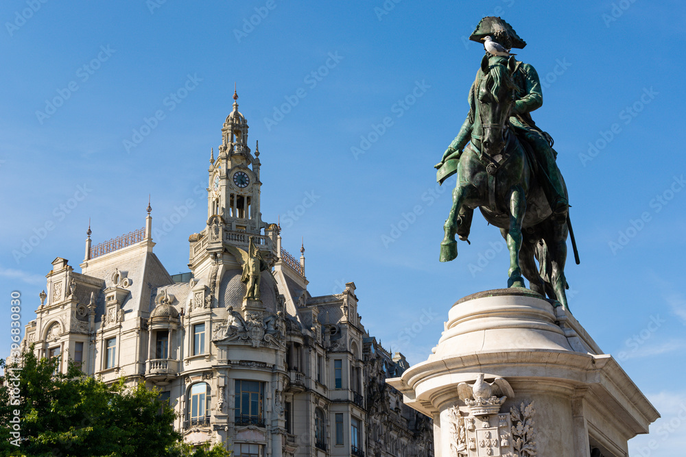 Man riding a horse with a seagull perched in its head. Antique building in the background. Statue of D. Pedro IV. Blue sky. Porto