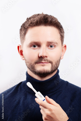 Man holding oral HIV test on blue background.