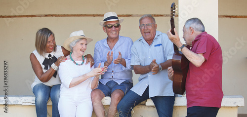 Obraz na plátně Gruppo di anziani vitali canta e suona con la chitarra una canzone seduti in una