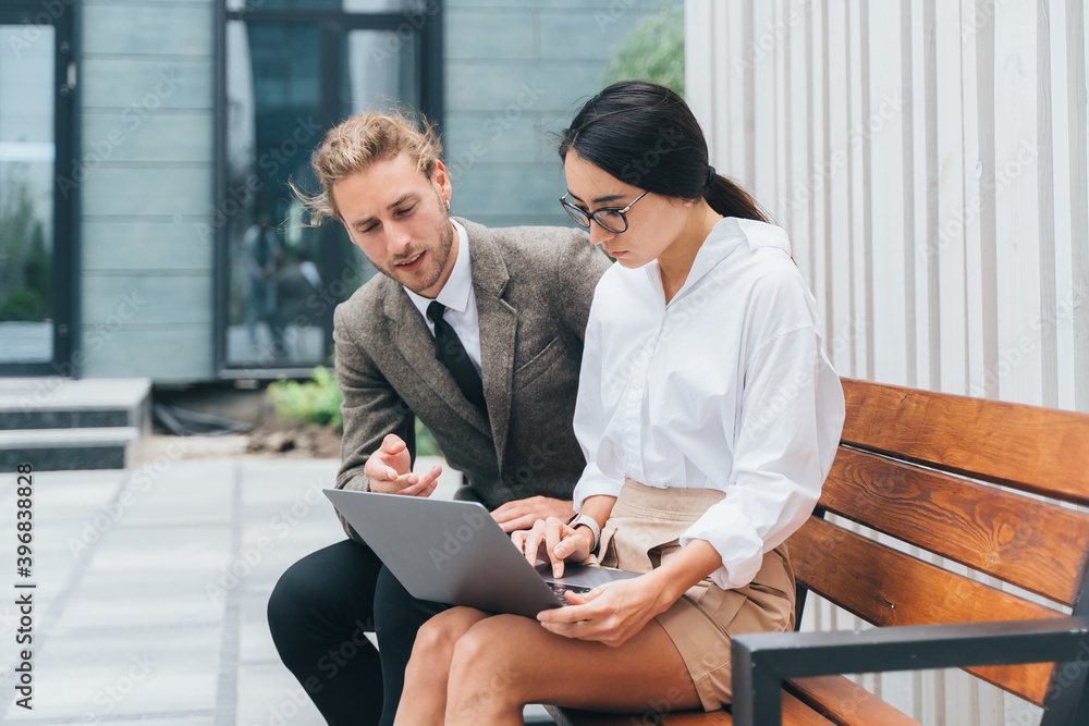 asian girl and man in business clothes on a bench with a laptop are discussing
asian girl and man in business clothes on a bench with a laptop are discussing
