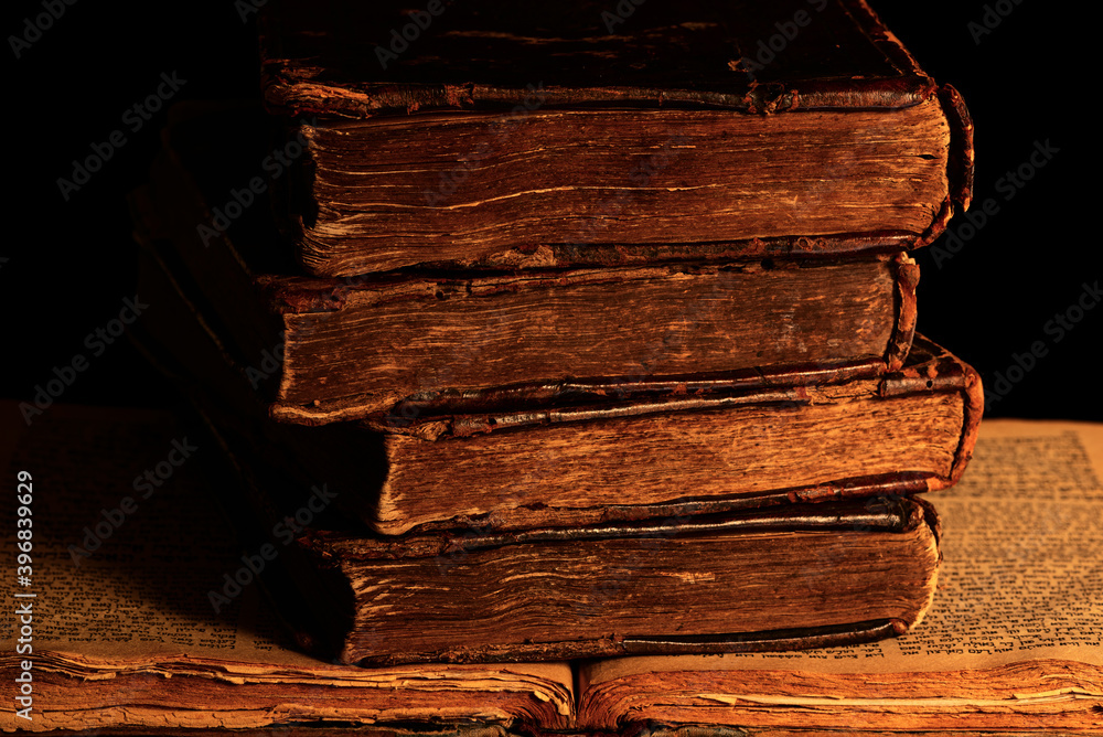 Φωτογραφία Stack of old shabby Jewish books in leather binding on the open pages of Machzor in the dark